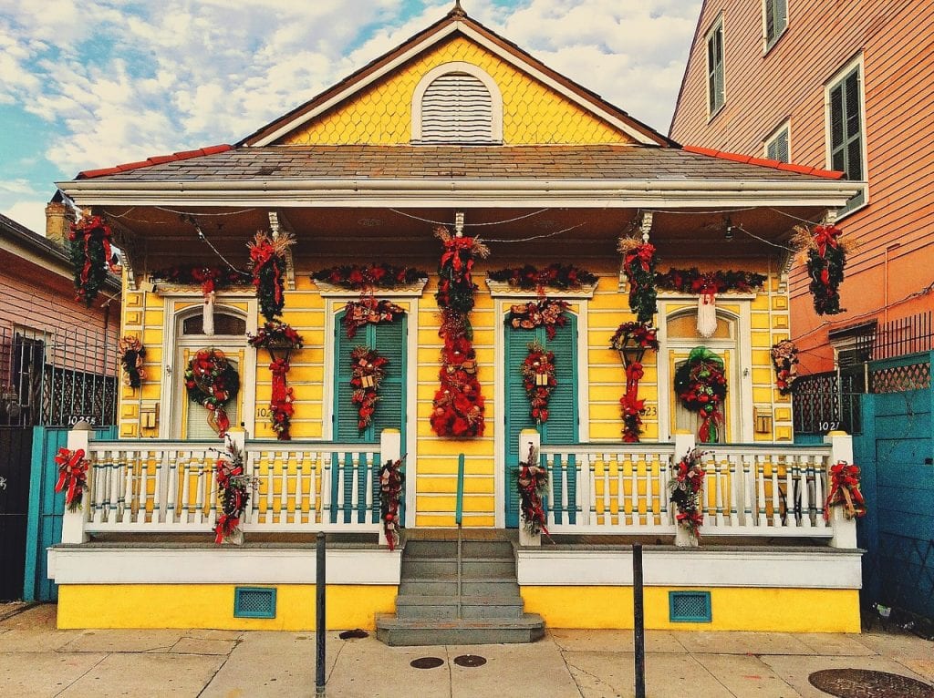 A yellow house in New Orleans draped with orange fall decor.