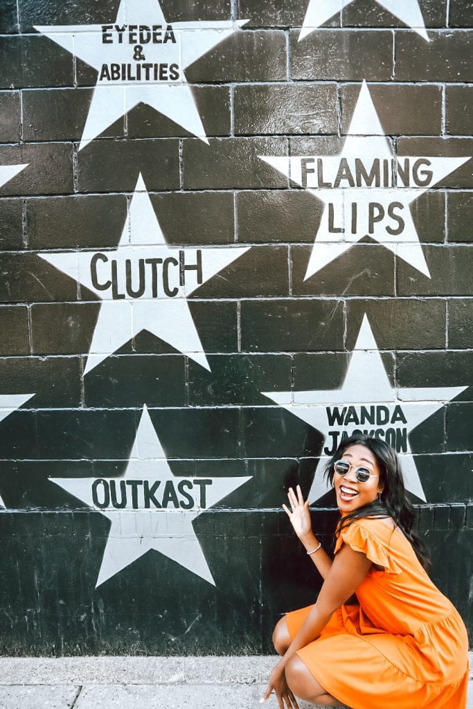 Girl in orange dress in front of Stars street art
