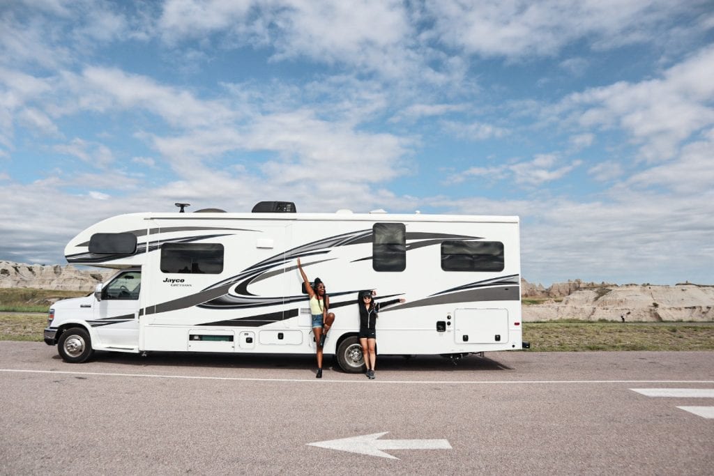 Two girls standing in front of a white RV on an RV road trip