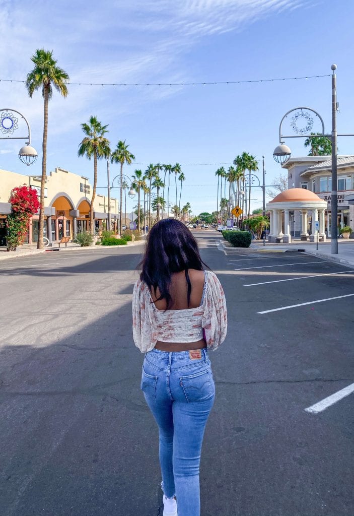 Girl walking down street with palm trees in background