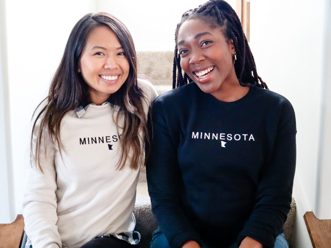 Two girls wearing embroidered MN sweatshirts 