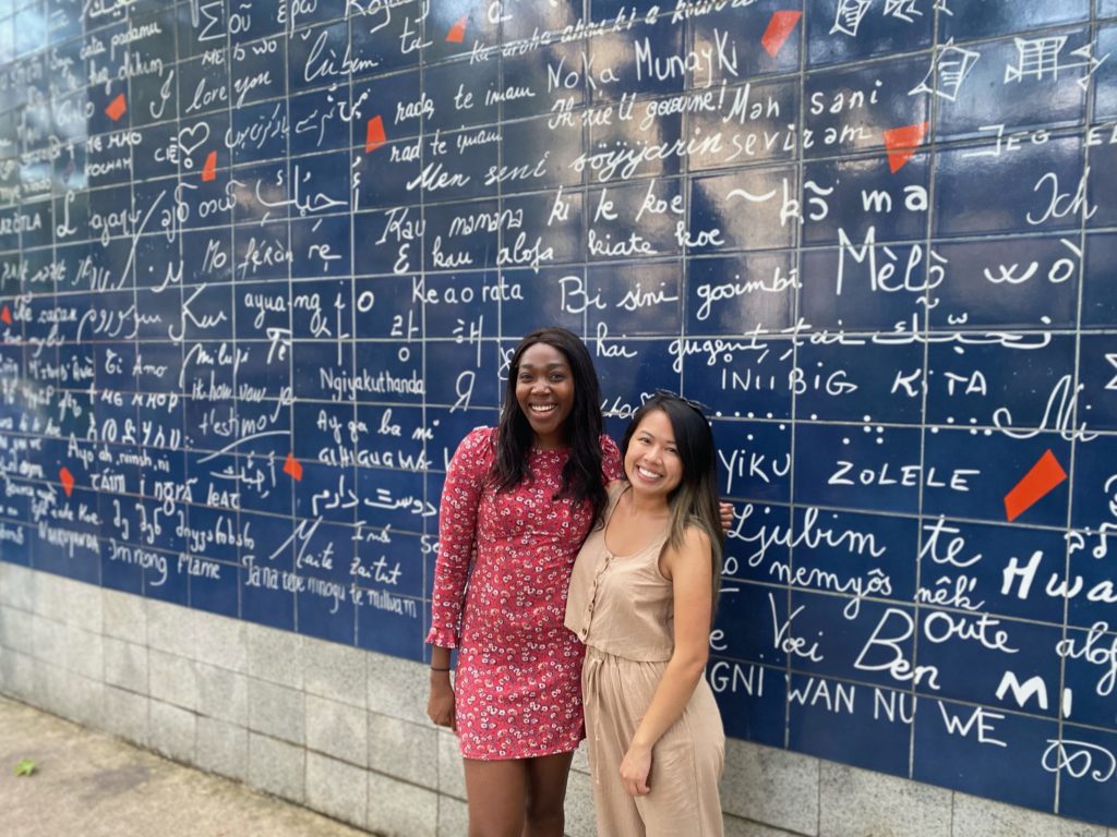 Two girls standing in front of Love Wall in Paris, France