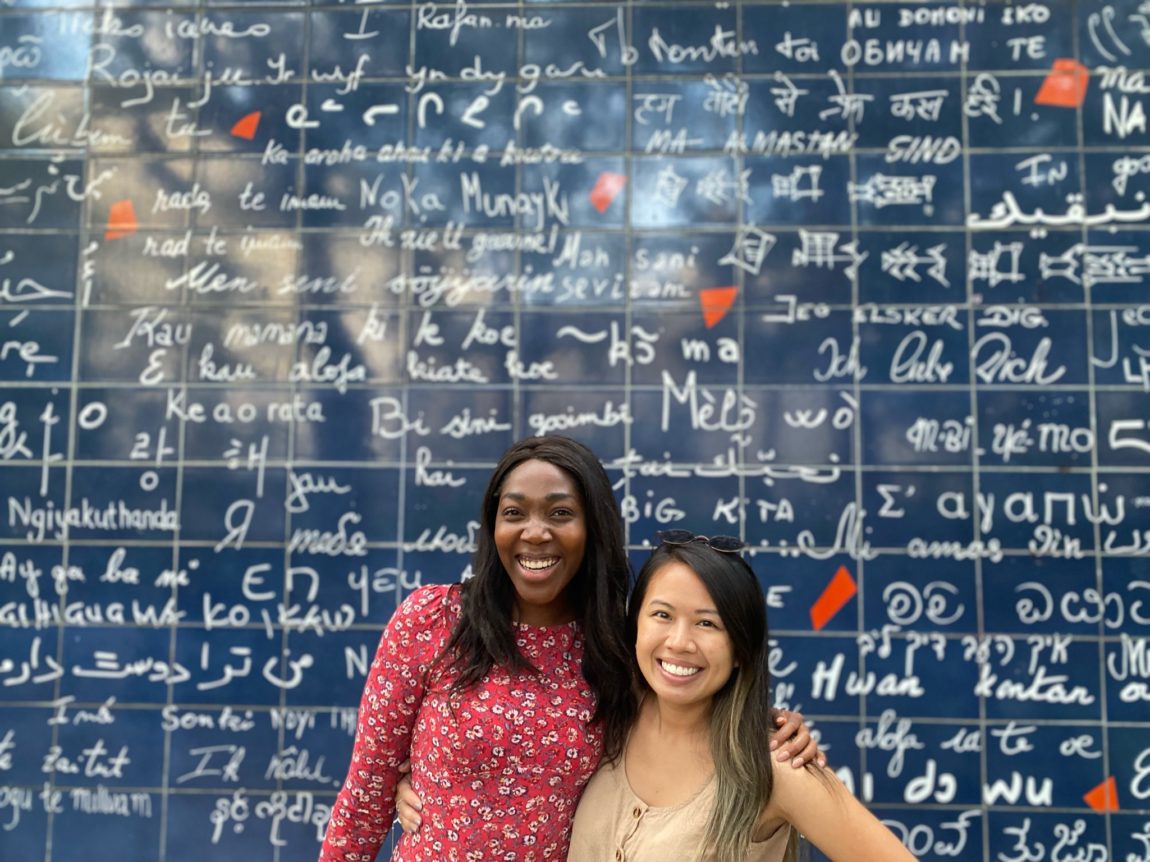 Two girls standing in front of the Love Wall in Paris