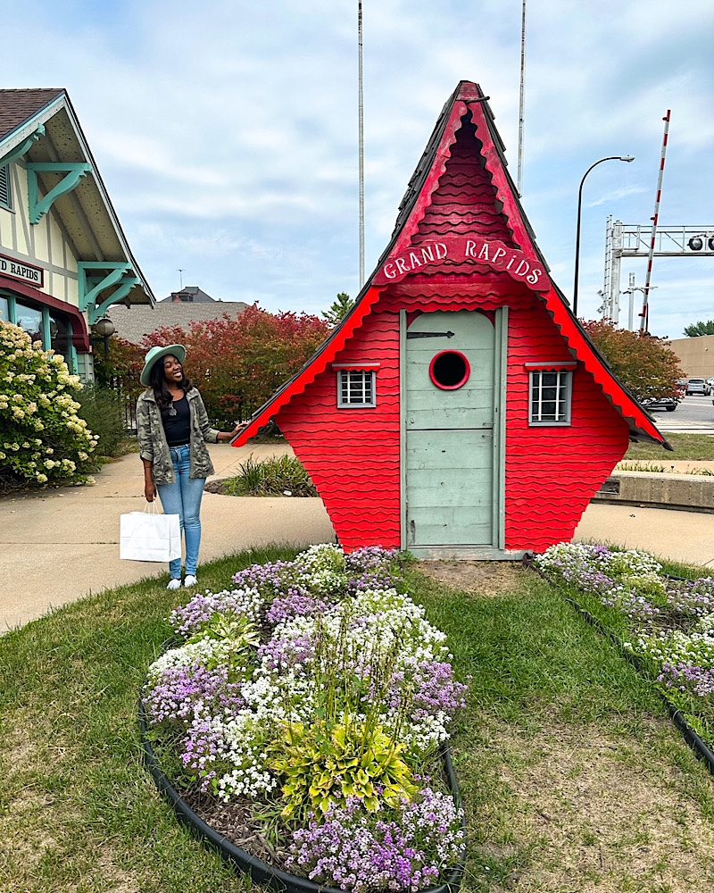 black woman standing next to a tiny red house in Grand Rapids Minnesota