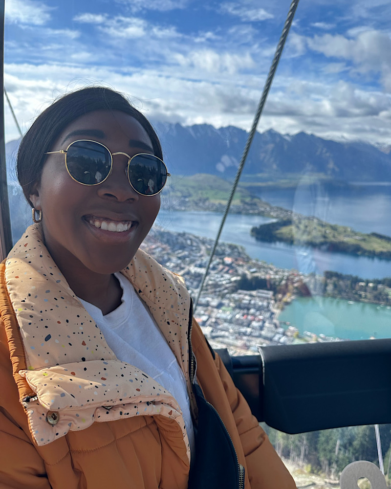 black woman in sunglasses in Gondola in Queenstown. Mountain view in the background