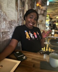 black woman smiling with a glass of wine in Auckland speakeasy